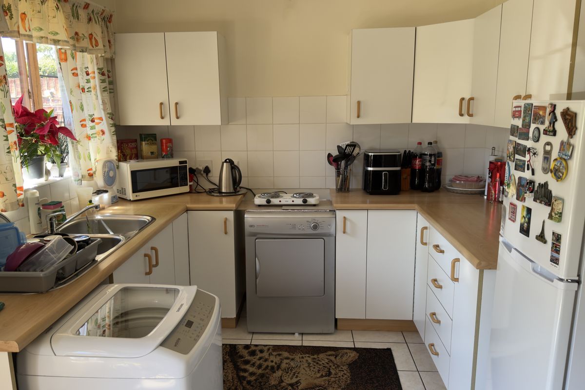 A functional kitchen featuring white cabinetry, laminate countertops, tiled backsplash, and tiled flooring, providing a practical layout for daily meal preparation.