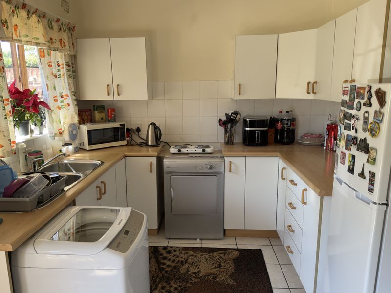 A functional kitchen featuring white cabinetry, laminate countertops, tiled backsplash, and tiled flooring, providing a practical layout for daily meal preparation.