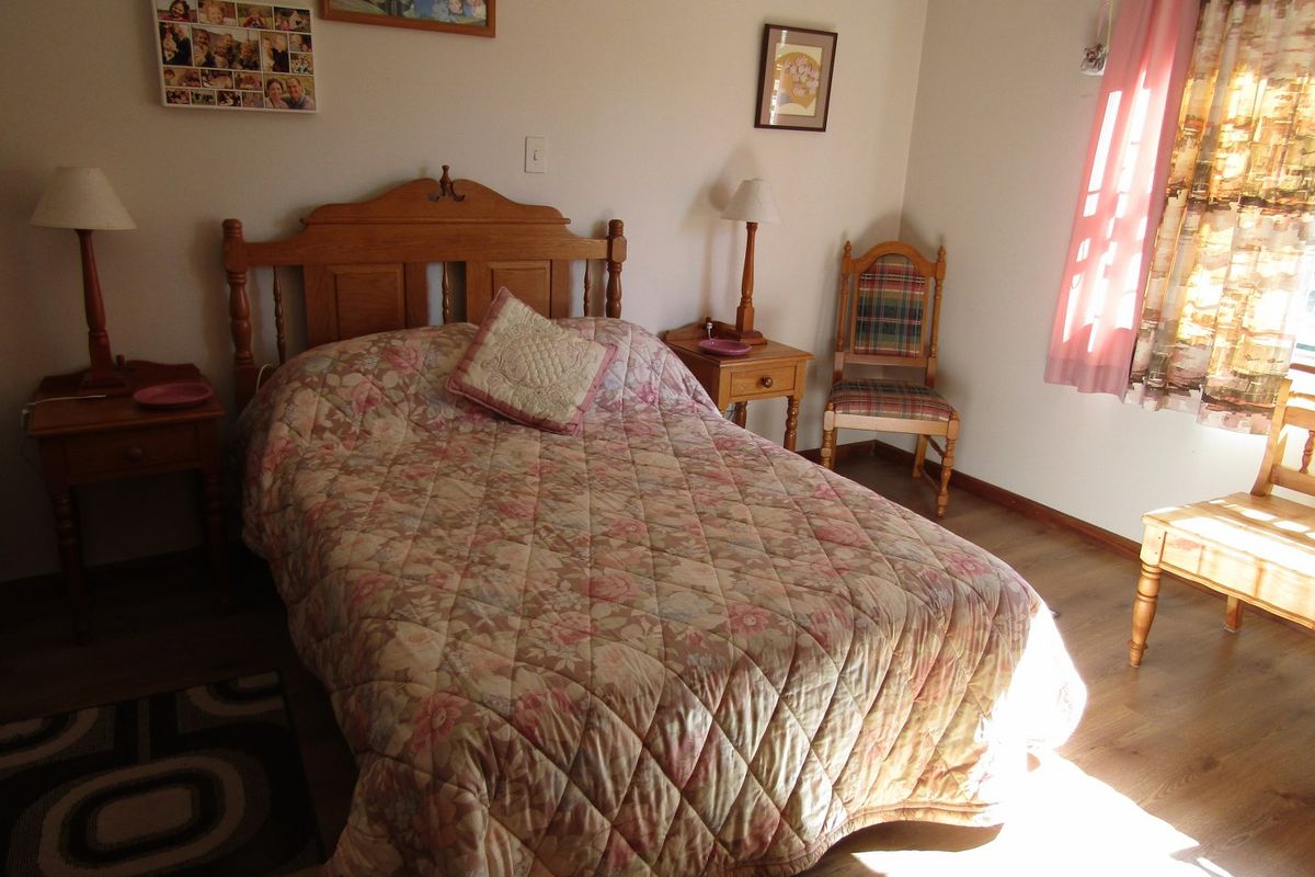 A bedroom featuring laminate flooring and natural light from a side window.
