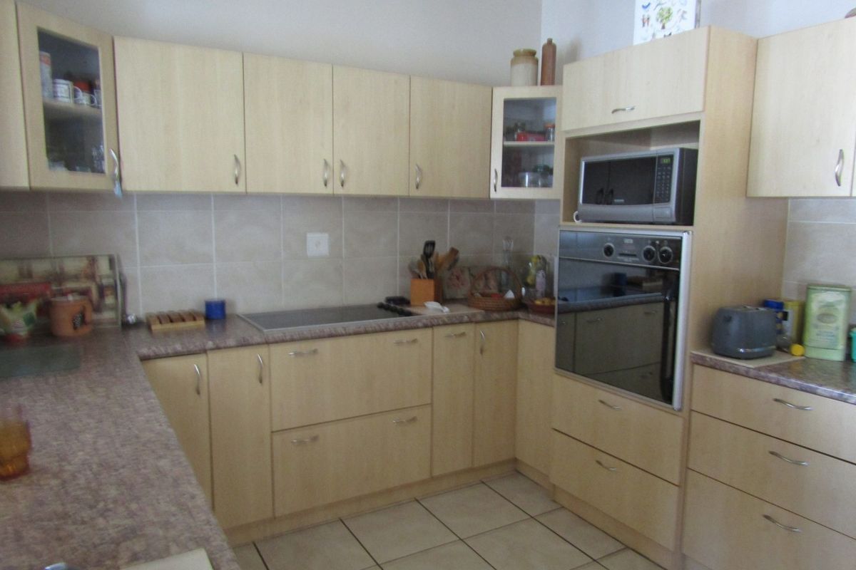 Functional kitchen featuring light wood-tone cabinetry, laminate countertops, ceramic tile backsplash, and integrated appliances including an oven and microwave.