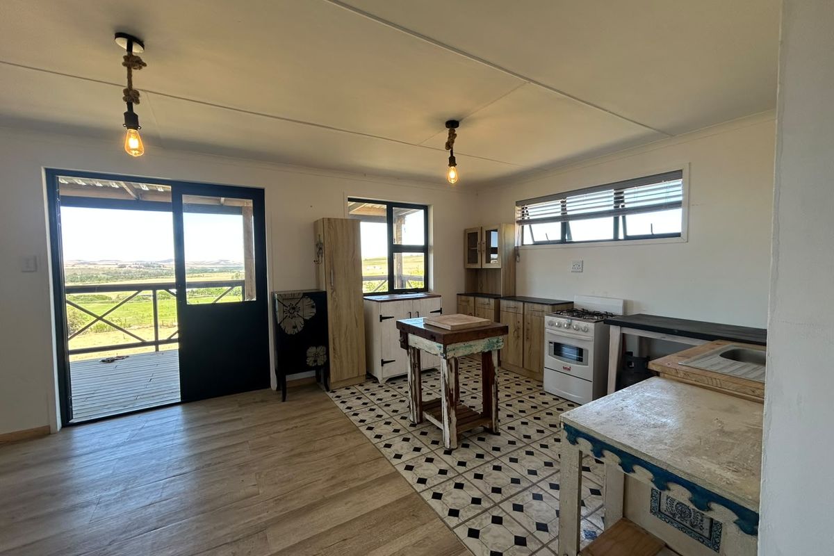 Open-plan kitchen featuring a gas stove, patterned tile flooring, and direct access to an outdoor deck with scenic farm views.
