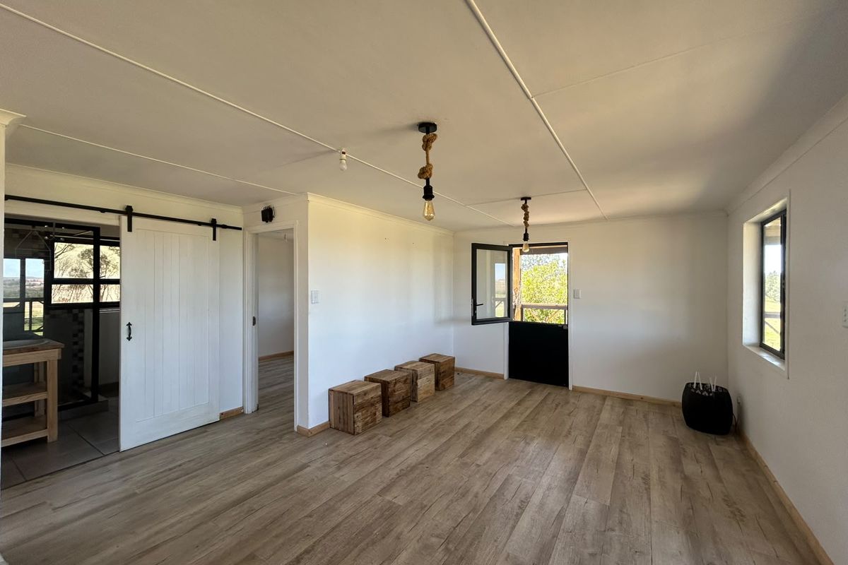 A bright, open-plan living area featuring modern laminate flooring, a classic barn-style sliding door, and a charming stable-style door leading outdoors.