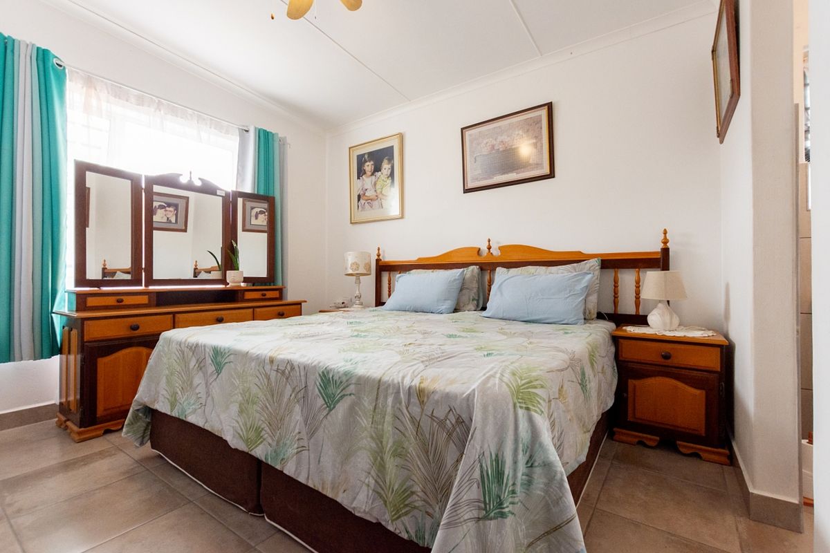 A well-maintained bedroom featuring tiled flooring and a ceiling fan, offering a comfortable and functional living space.
