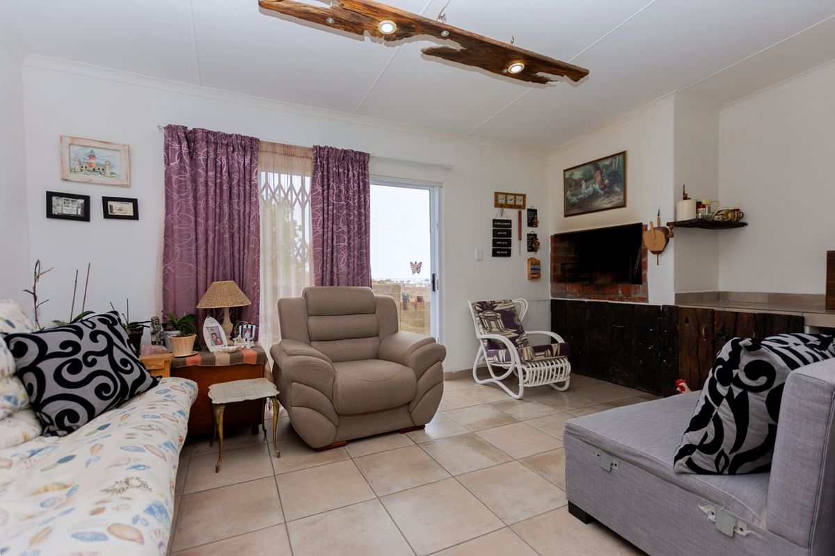 A living room featuring tiled flooring, a built-in fireplace, and a sliding glass door with security gate leading to the exterior.