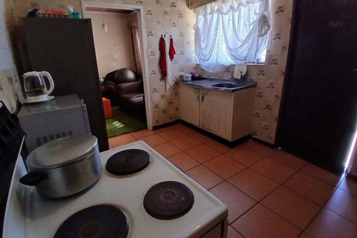 A functional kitchen featuring tiled flooring, built-in cabinetry, and a sink, currently showing signs of age and wear.