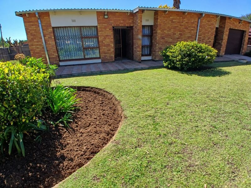 Front view of a face brick house featuring a paved patio, security gates, and a well-maintained garden with a manicured lawn.