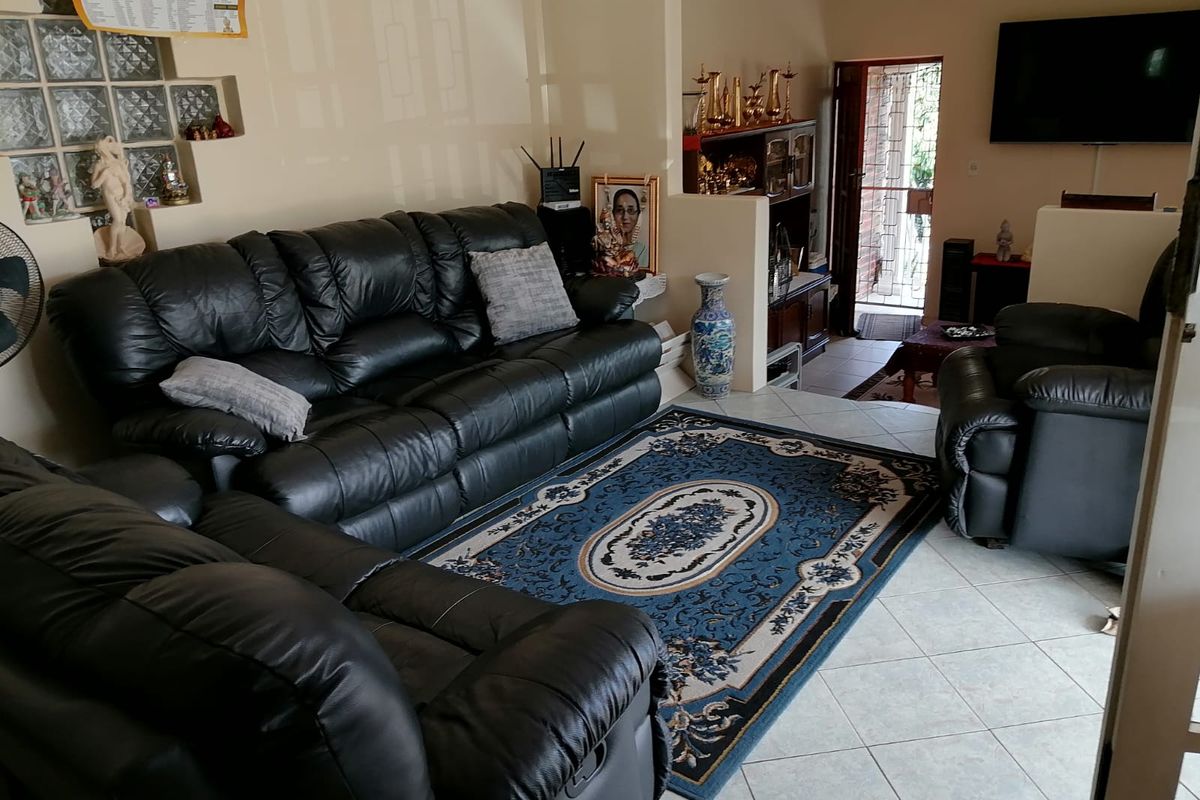 A living room featuring tiled flooring, a glass block feature wall, and an open-plan layout leading to the entrance.