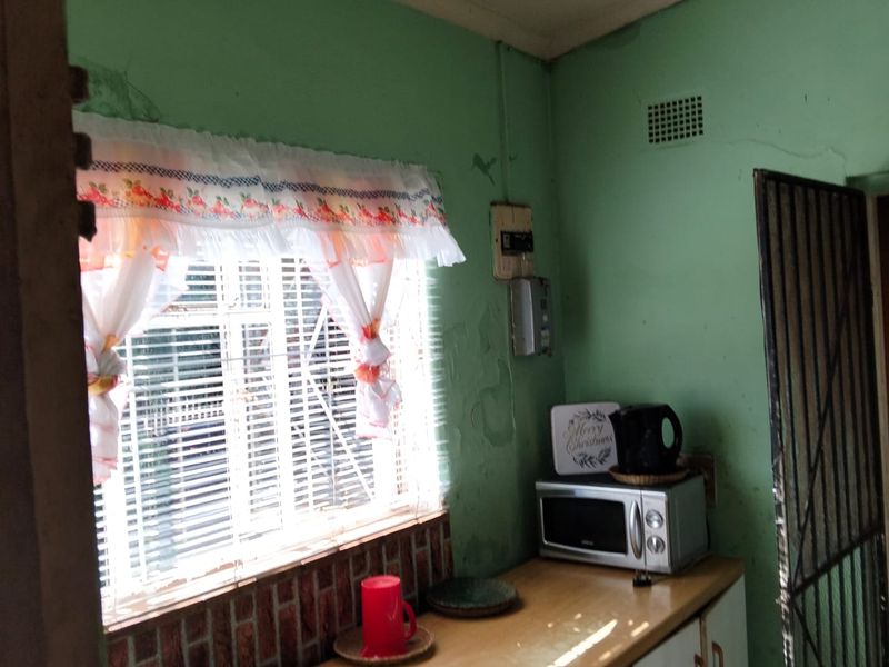 A small kitchen area featuring built-in cabinetry and a countertop, currently showing significant wear to the wall finishes and paintwork.