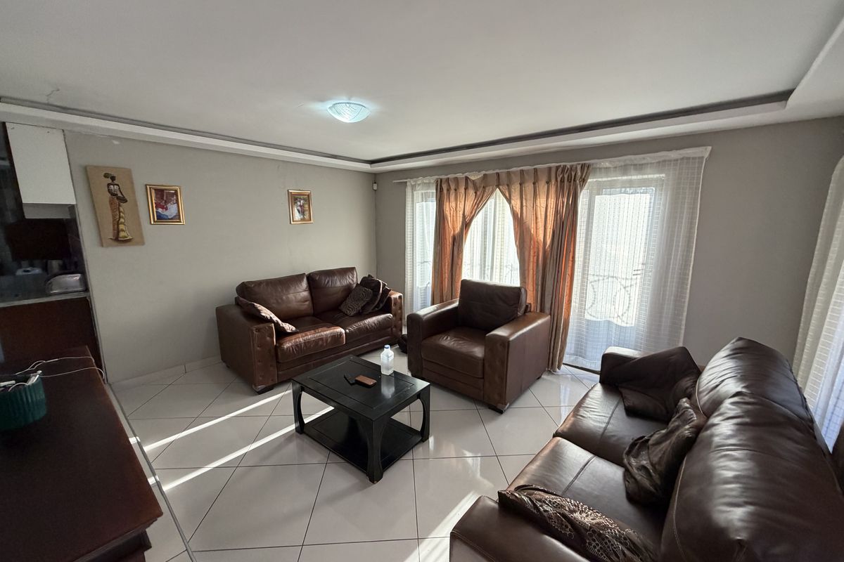 A spacious living room featuring tiled flooring, neutral wall tones, and a sliding glass door providing access to the exterior.