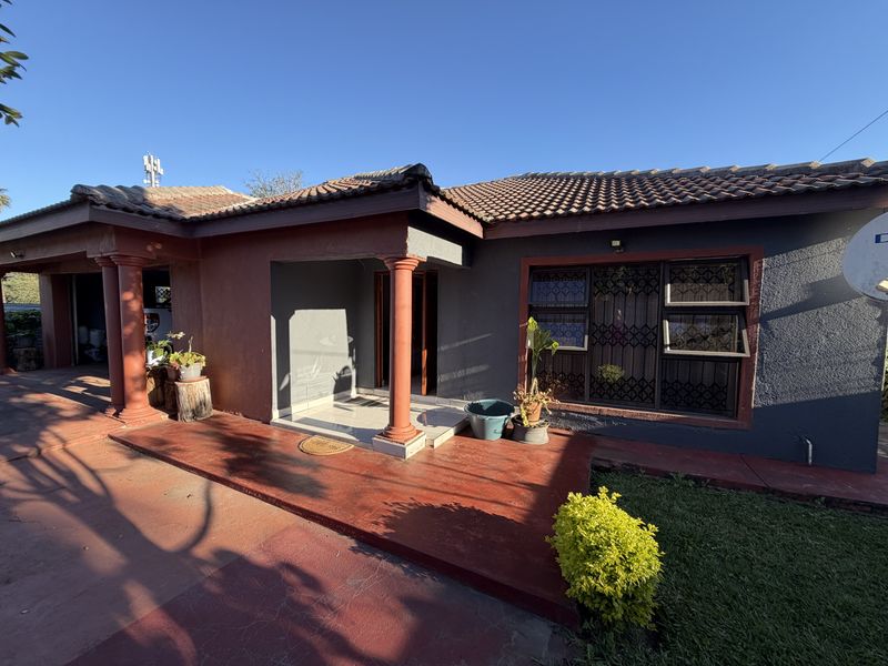 Front elevation of a single-story house featuring a covered entrance, tiled roof, and paved driveway area.