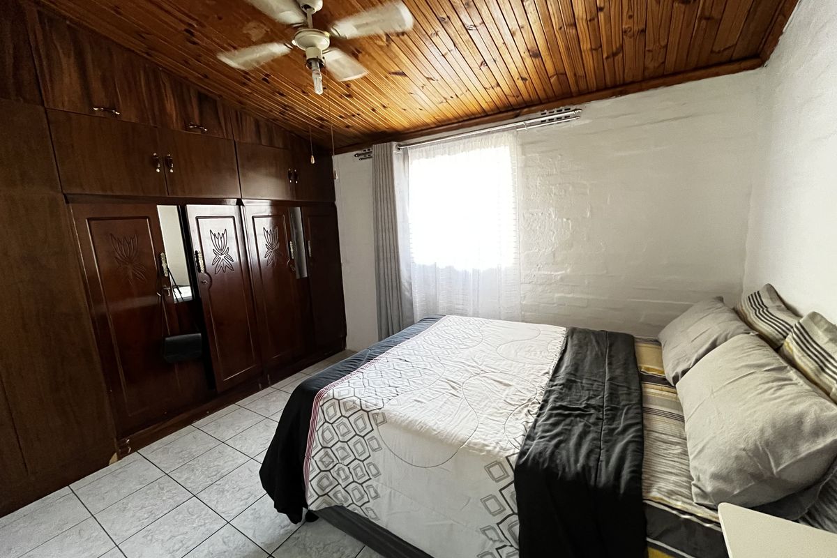 A bedroom featuring a timber ceiling, ceiling fan, tiled flooring, and extensive built-in wooden cabinetry for storage.