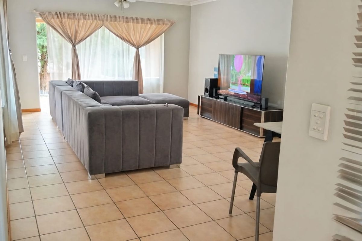 Spacious living room featuring ceramic tile flooring, a ceiling fan, and large sliding glass doors providing natural light.