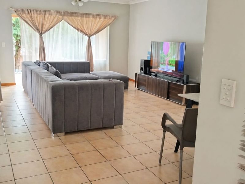 Spacious living room featuring ceramic tile flooring, a ceiling fan, and large sliding glass doors providing natural light.