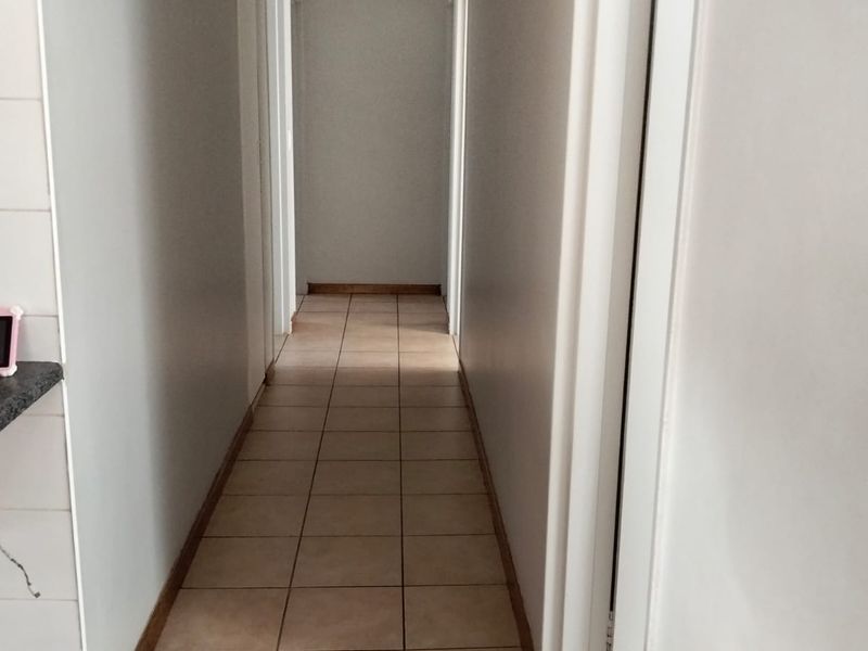 A functional hallway featuring neutral tiled flooring and clean wall finishes, providing access to various rooms within the home.