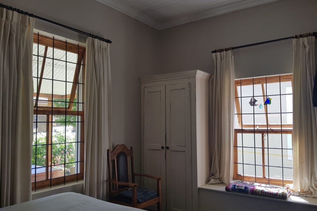 A bedroom featuring timber-framed windows with security bars, a built-in cupboard, and a tongue and groove ceiling.