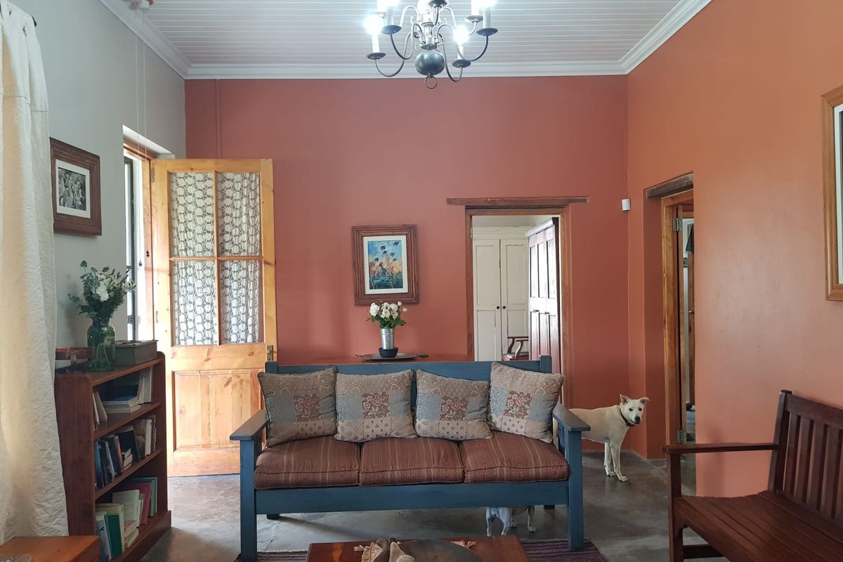 A living room featuring terracotta-toned walls, a timber-paneled ceiling, and traditional timber door frames, offering a warm and rustic aesthetic.