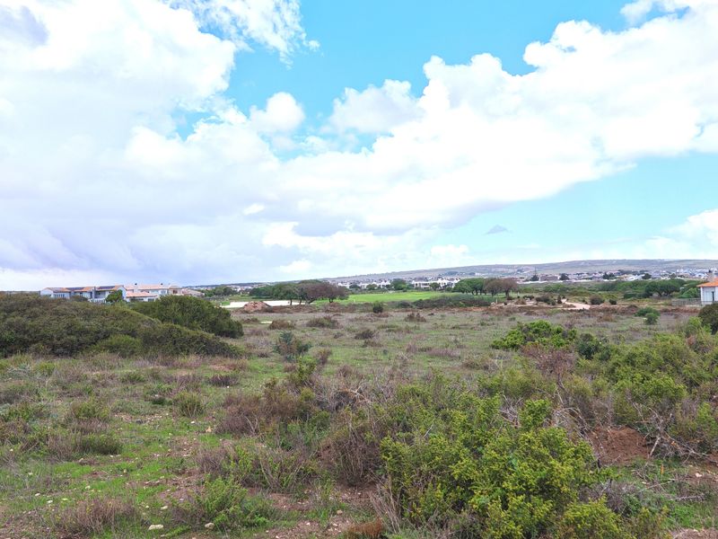 A wide-angle view of the surrounding natural landscape and coastal terrain, showcasing the open environment and distant residential development.