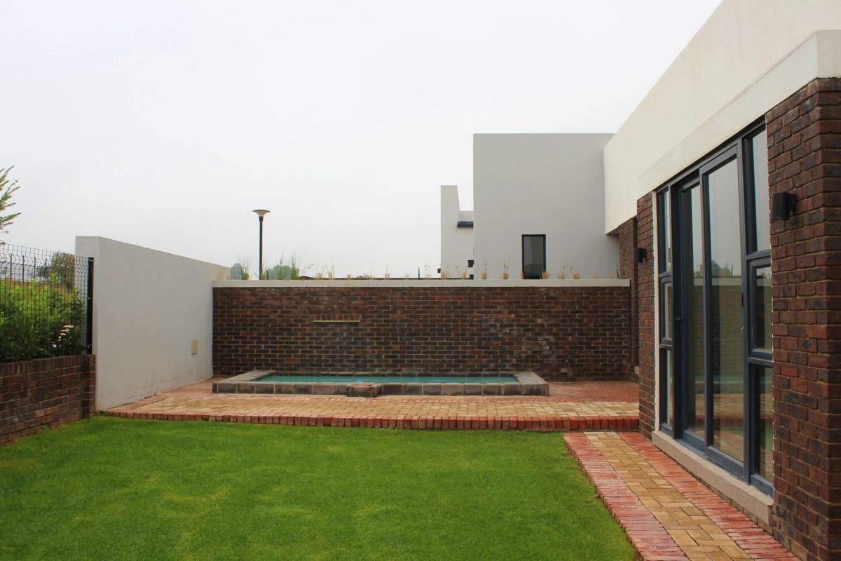 Rear garden area featuring a small plunge pool, paved patio space, and a brick boundary wall, accessible via large sliding glass doors.