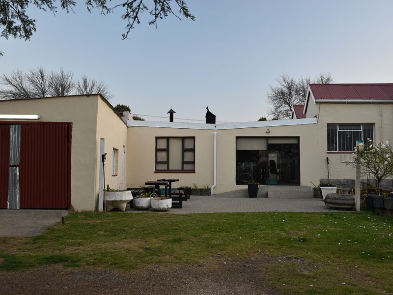 Rear view of the property featuring a paved patio area, attached garage, and access to the main dwelling with security features.