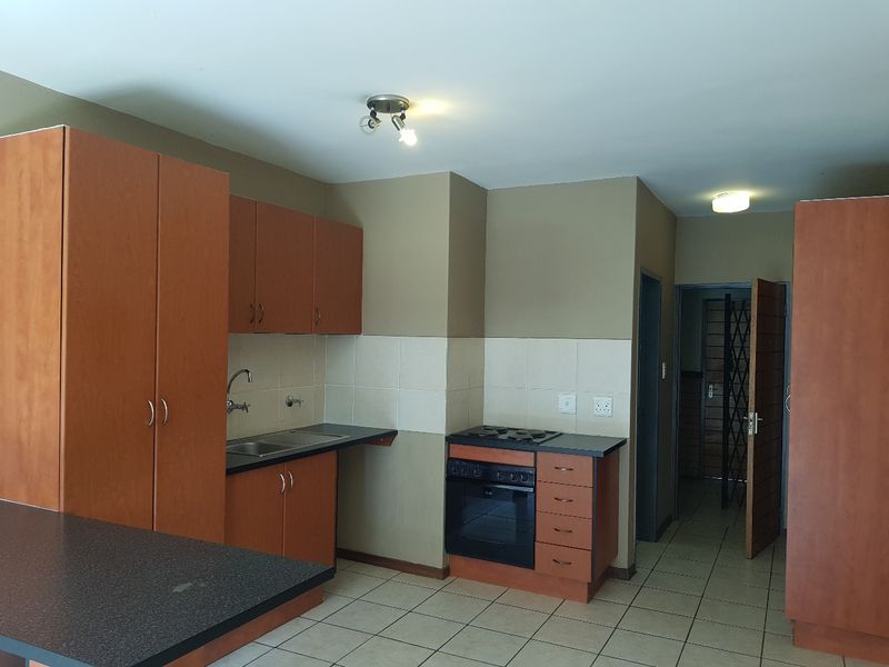 A functional kitchen featuring built-in wooden cabinetry, laminate countertops, a built-in oven with hob, and tiled flooring.