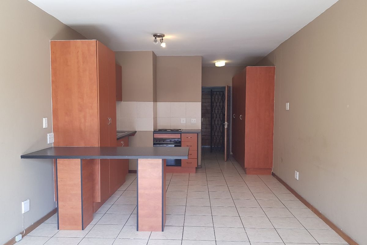 A functional kitchen featuring built-in cabinetry, a breakfast bar, and a built-in oven with hob, set against a neutral tiled floor.
