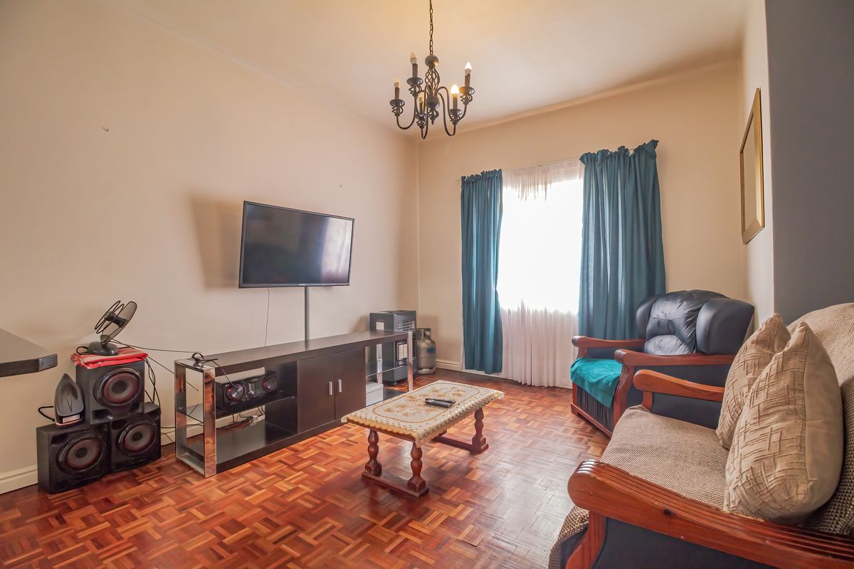 A cozy living room featuring classic parquet flooring and a central ceiling light fixture, providing a warm and traditional foundation for the space.