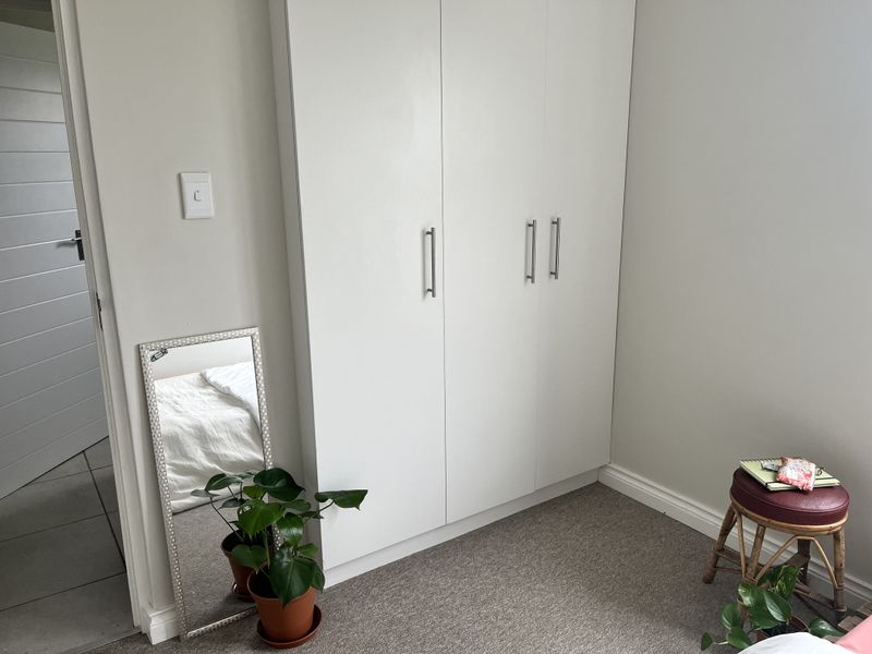 A clean bedroom featuring a modern white built-in wardrobe and neutral carpet flooring.