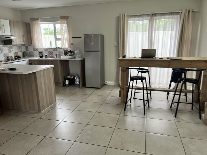 Open-plan kitchen and living area featuring modern wood-look cabinetry, tiled flooring, and direct access to the outdoors via sliding glass doors.