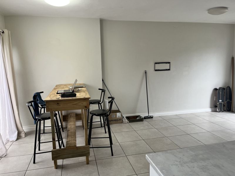 Open plan living area featuring neutral wall tones and tiled flooring, providing a versatile space for dining or relaxation.