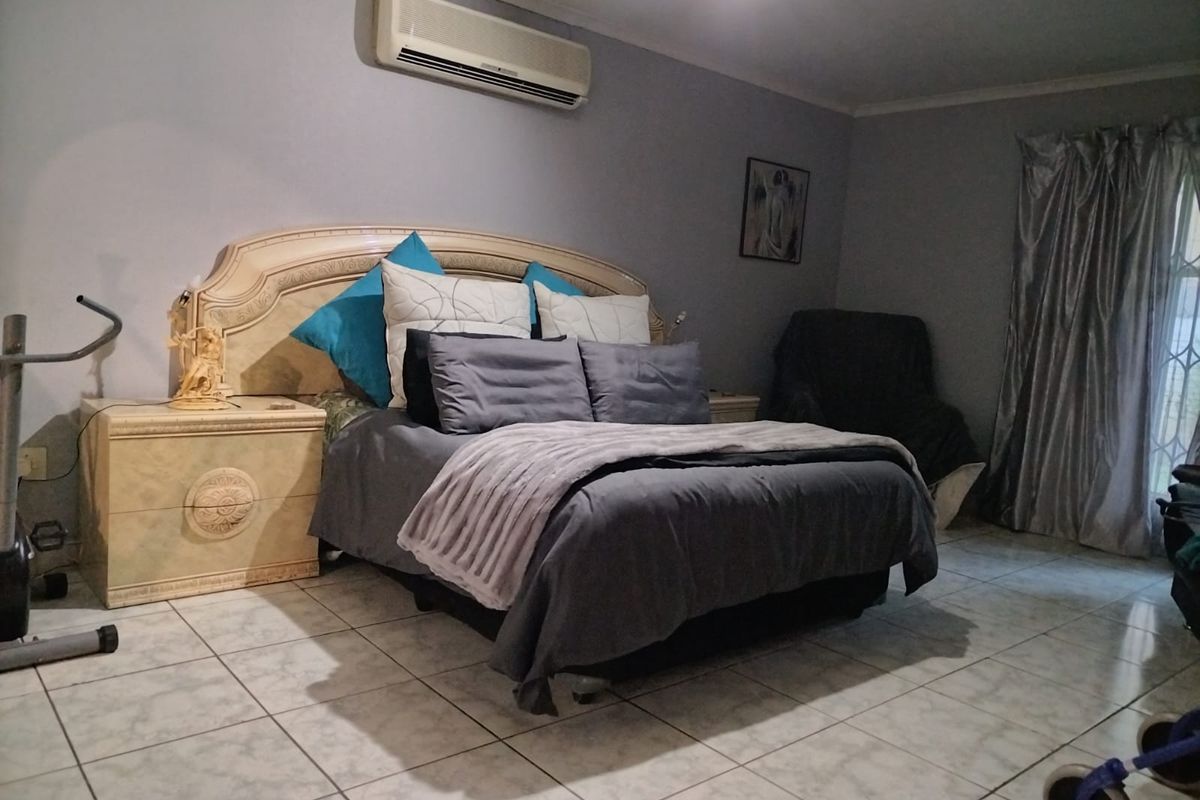 A bedroom featuring tiled flooring and a wall-mounted split-system air conditioning unit.