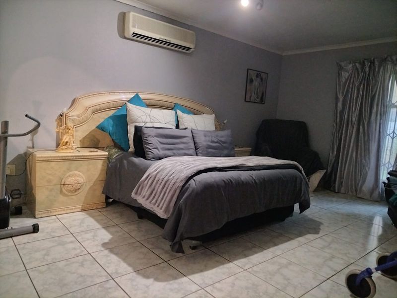 A bedroom featuring tiled flooring and a wall-mounted split-system air conditioning unit.