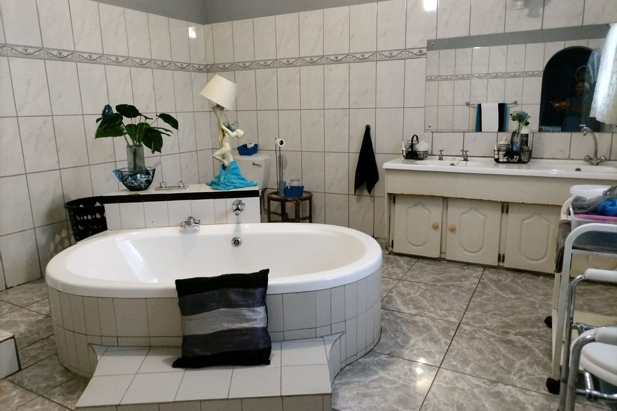 Spacious bathroom featuring a built-in oval bathtub, double vanity with basin, and full-height wall tiling.