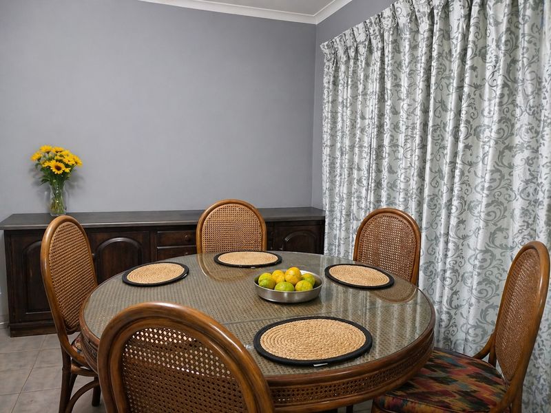 A dining room featuring tiled flooring, a built-in sideboard, and decorative window curtains.