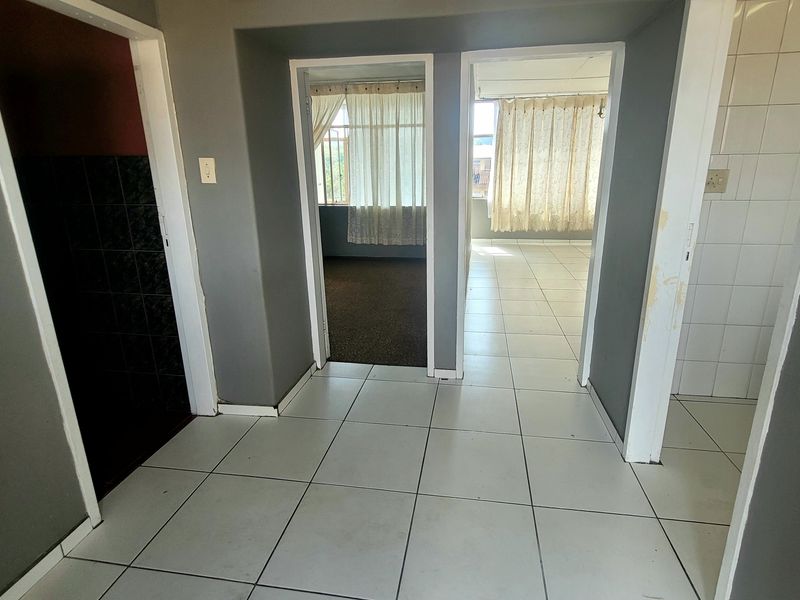 A central hallway with tiled flooring providing access to multiple rooms, featuring neutral grey walls and standard door frames.