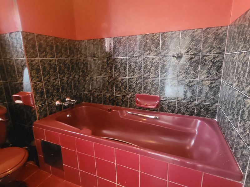 A dated bathroom featuring a built-in bathtub and tiled wall finishes, offering significant potential for a modern renovation.