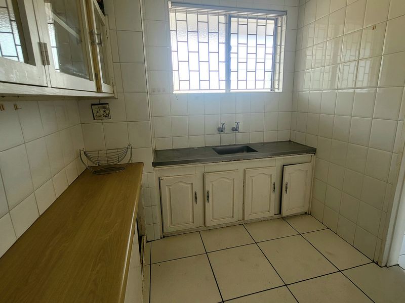 A functional kitchen space featuring built-in cabinetry, a stainless steel sink, and tiled wall finishes, ready for modernization.