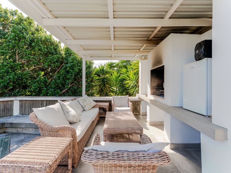 A covered outdoor patio featuring a built-in braai, concrete counter space, and tiled flooring, ideal for outdoor entertaining and relaxation.