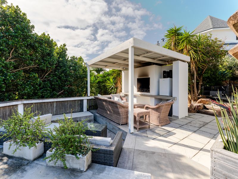 Outdoor patio area featuring a covered pergola with a built-in braai, ideal for alfresco dining and entertaining in a garden setting.