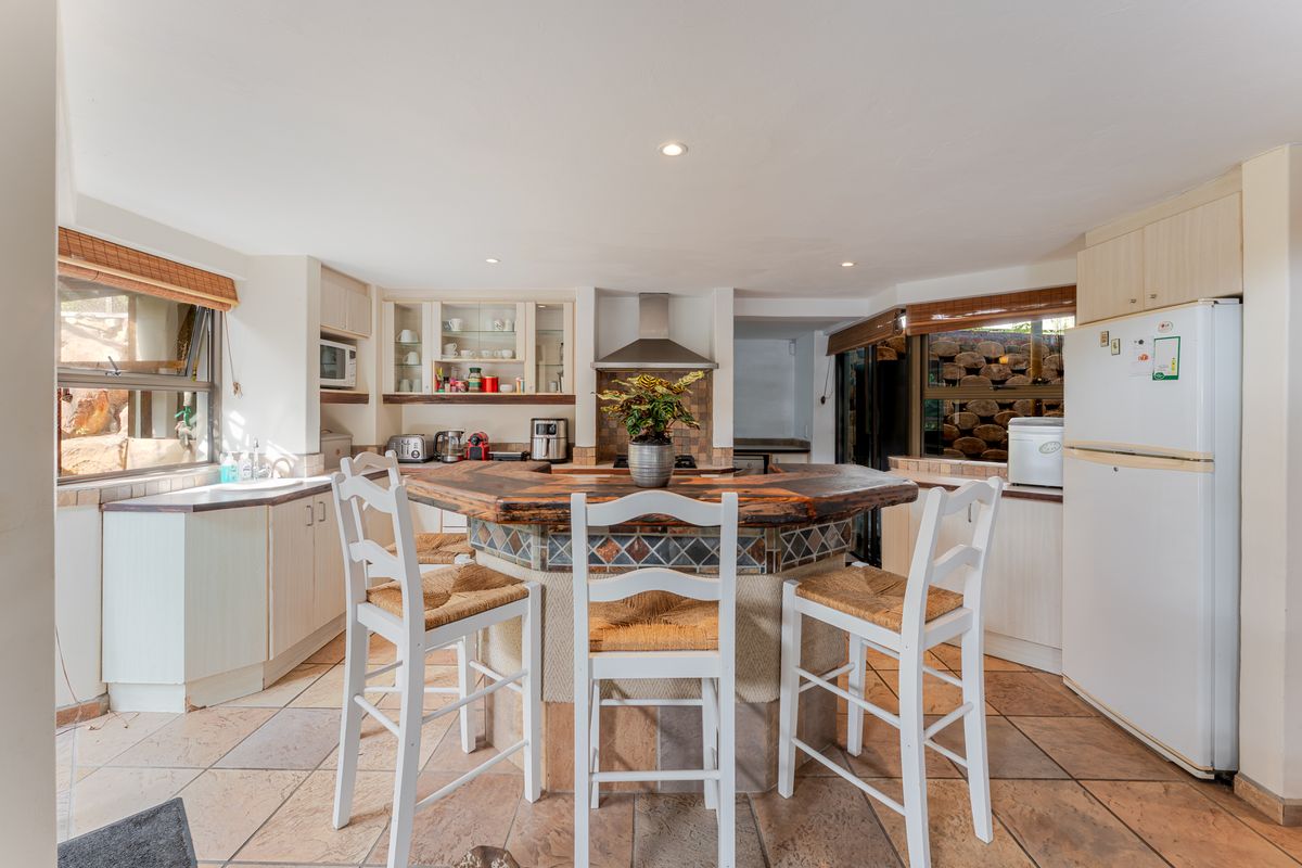 A functional kitchen featuring a central island with a wooden countertop, tiled flooring, built-in cabinetry, and a tiled backsplash.