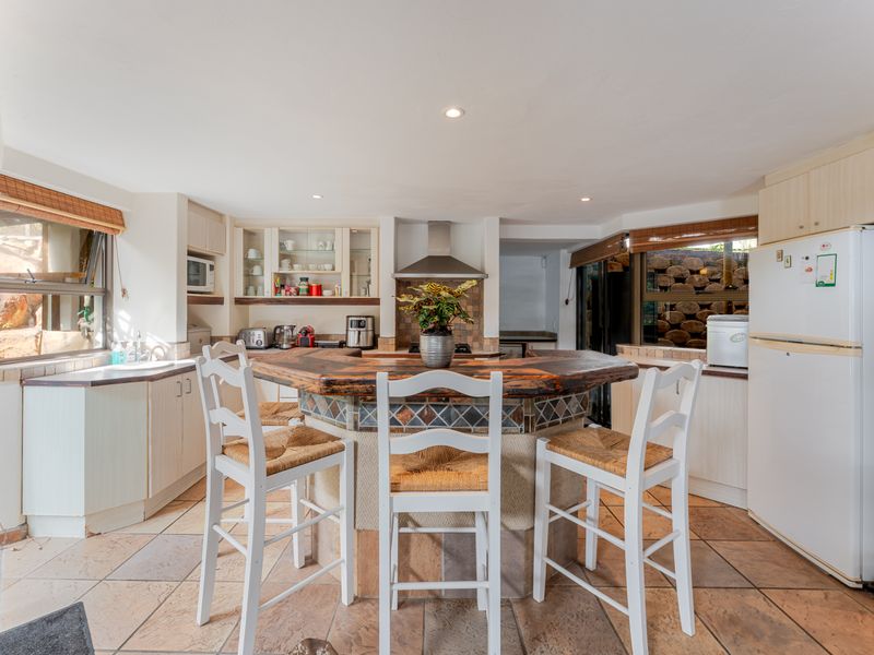 A functional kitchen featuring a central island with a wooden countertop, tiled flooring, built-in cabinetry, and a tiled backsplash.