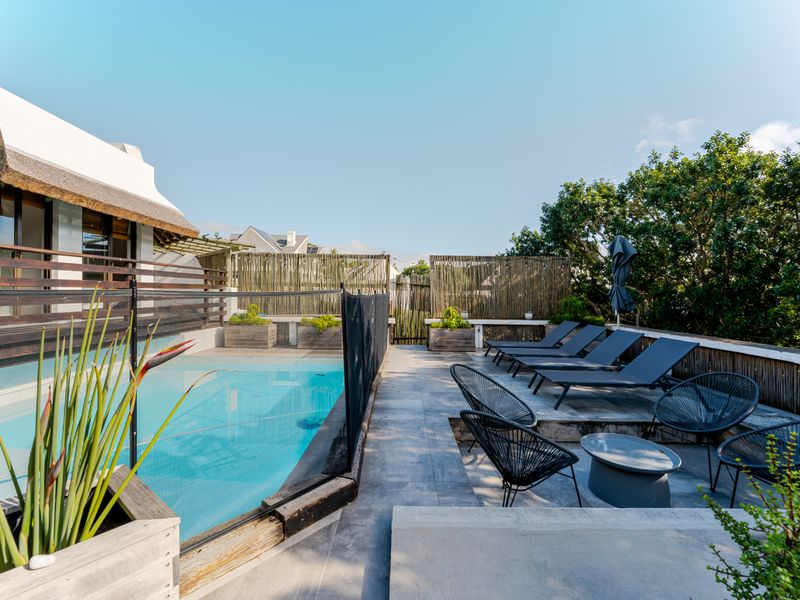 Outdoor pool area featuring a swimming pool with safety fencing, tiled decking, and timber perimeter screening.