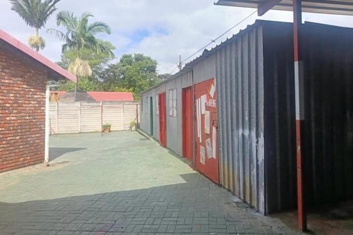 Rear courtyard area featuring a paved surface and a corrugated metal outbuilding structure with multiple access doors.