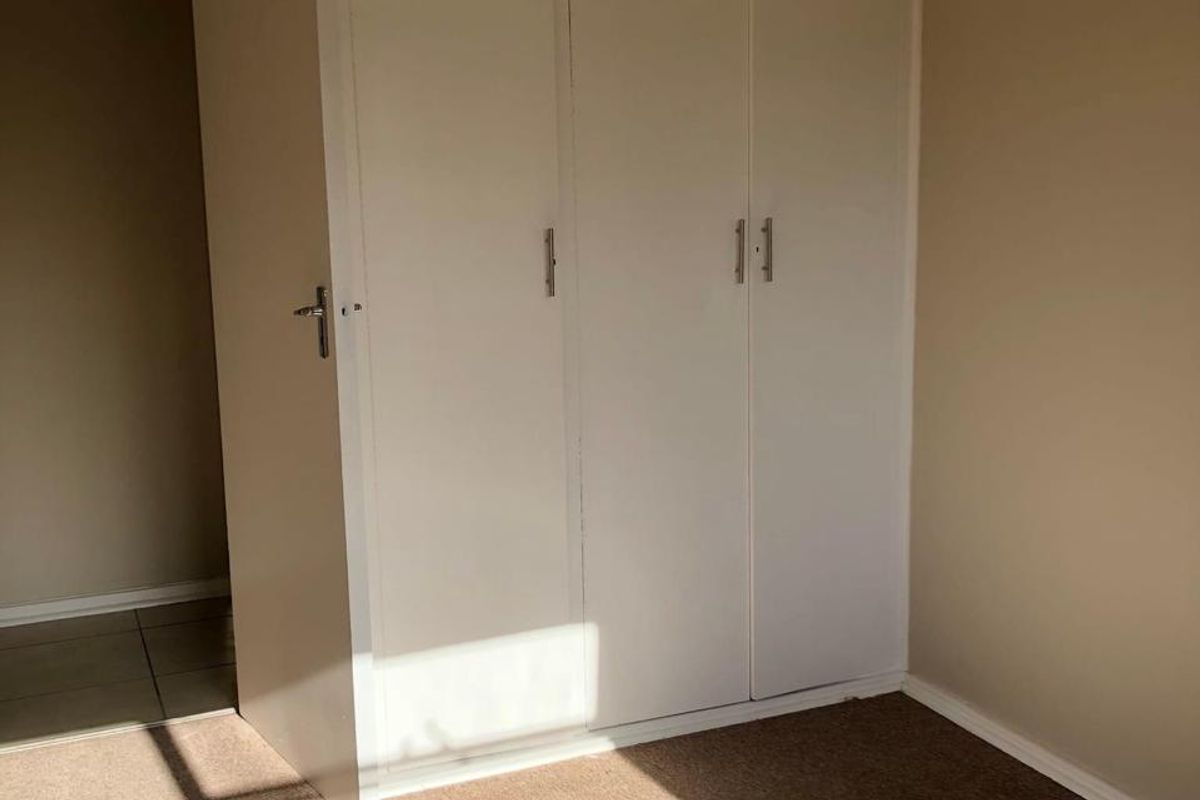 A simple bedroom featuring built-in cupboards and carpeted flooring, offering a clean and functional space ready for personalization.