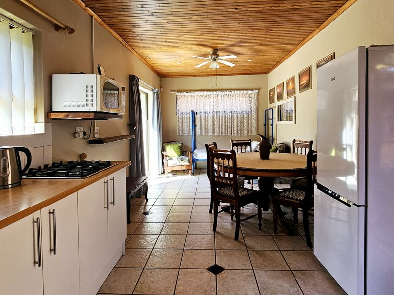 Open-plan kitchen and dining area featuring tiled flooring, timber ceiling, and gas hob, offering a functional layout for daily living.