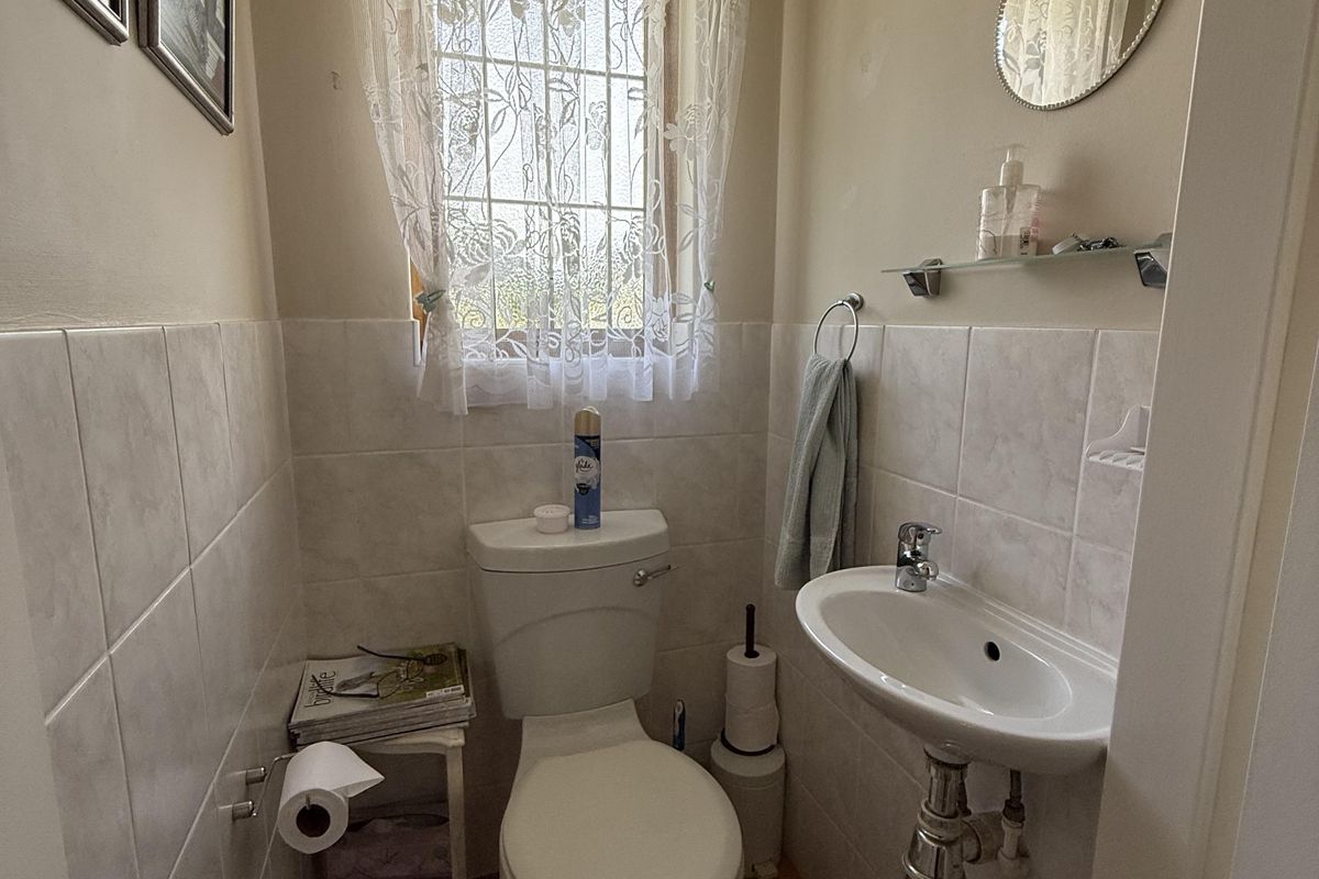 A compact guest bathroom featuring a wall-mounted basin, toilet, and neutral tiled finishes, providing a functional and well-maintained space.