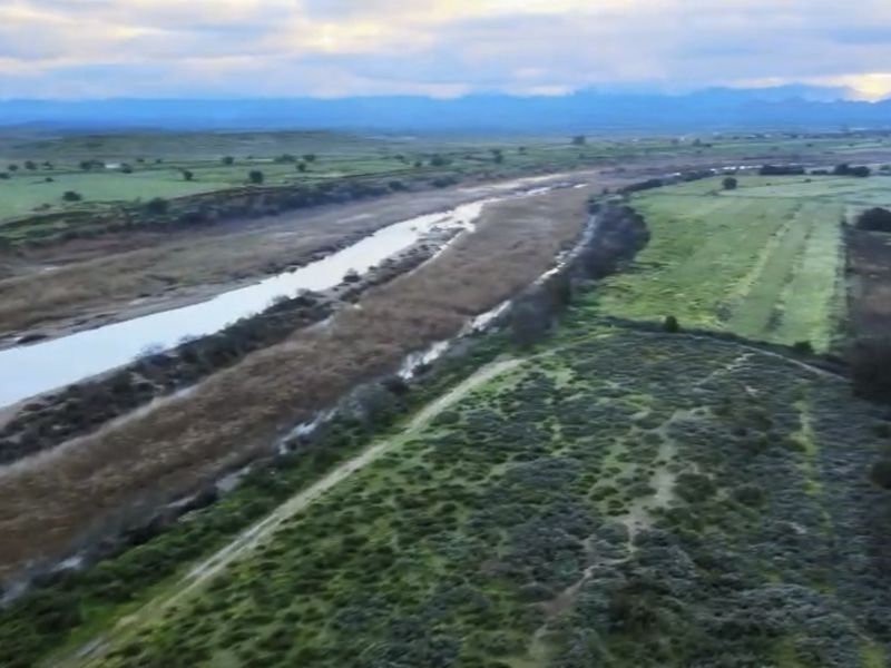 An aerial view of the expansive farm property featuring a river running through the landscape and surrounding agricultural fields.