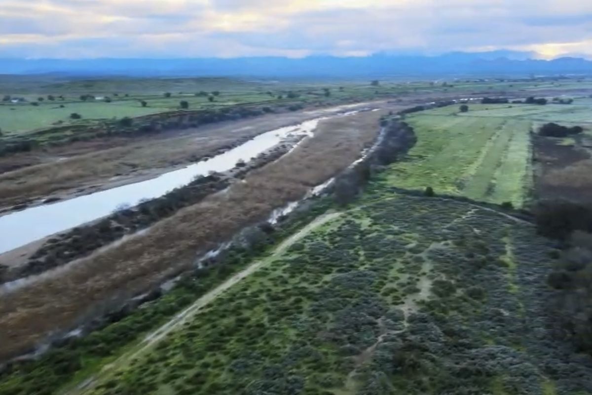 An aerial view of the expansive farm property featuring a river running through the landscape and surrounding agricultural fields.