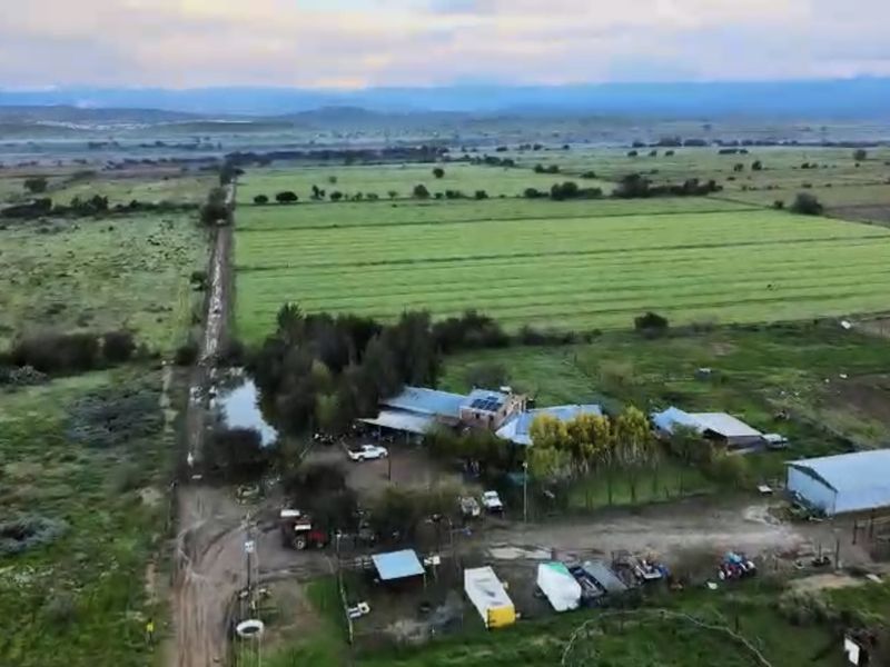 Aerial view of a rural farm property featuring multiple outbuildings, agricultural land, and solar panel installations.