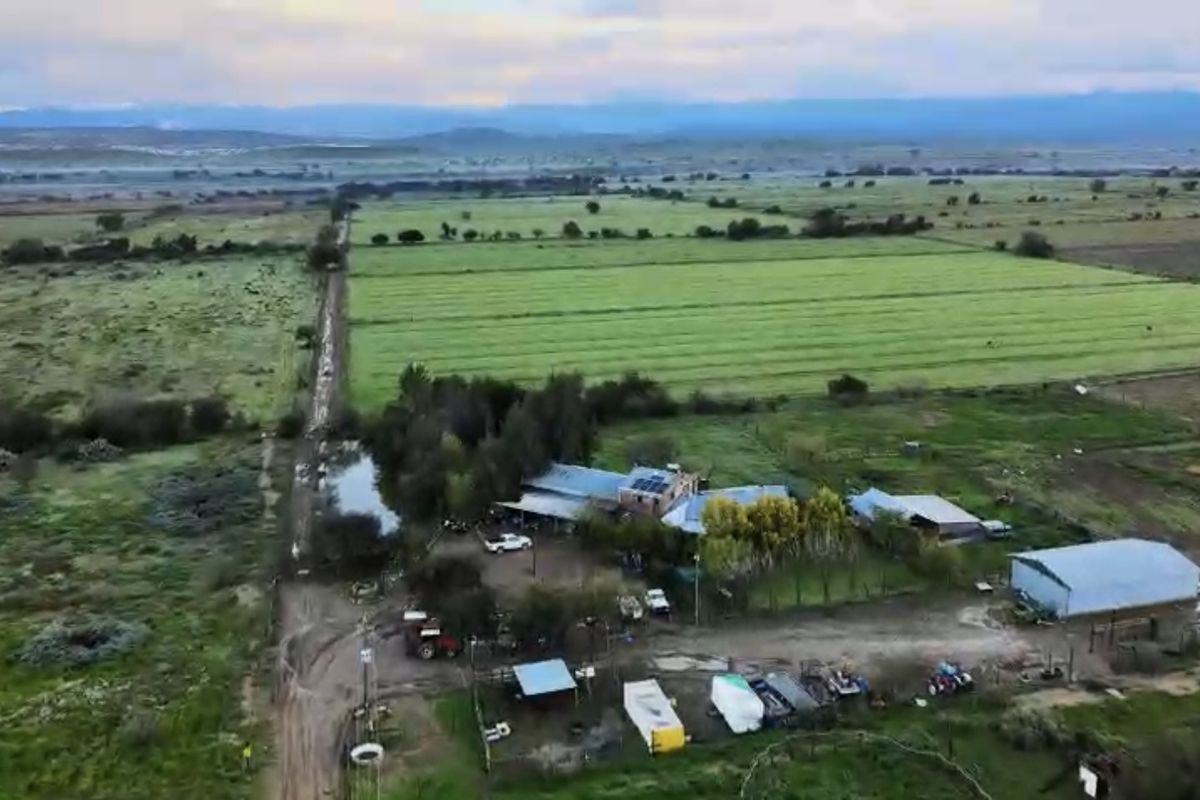 Aerial view of a rural farm property featuring multiple outbuildings, agricultural land, and solar panel installations.