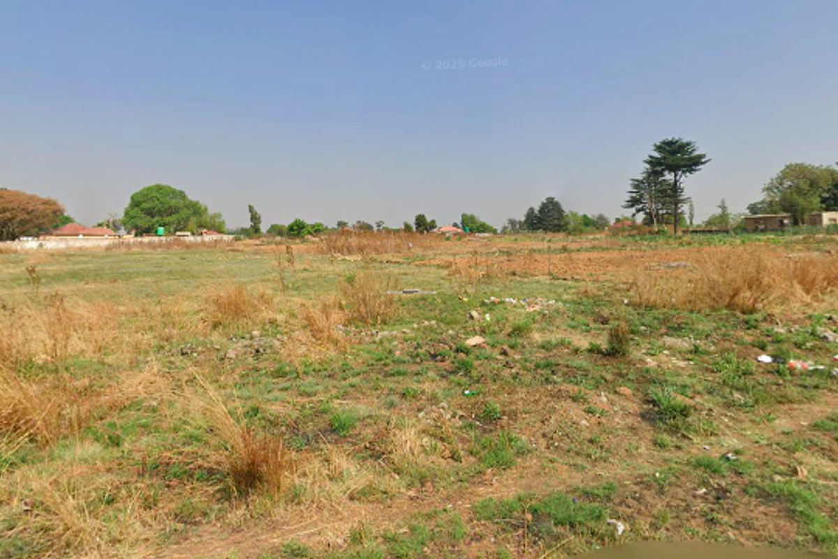 A wide-angle view of a vacant residential plot featuring open grassland and natural terrain, suitable for future development.